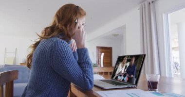 Beyaz bir kadın iş arkadaşlarıyla konuşurken bilgisayar ve kulaklık kullanıyor. Karantina süresince evde tek başına kalmak..