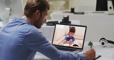 Beyaz erkek öğretmen okul çocuğuyla video görüşmesinde dizüstü bilgisayar kullanıyor. Çevrimiçi eğitim karantina süresince evde tek başına kalıyor..