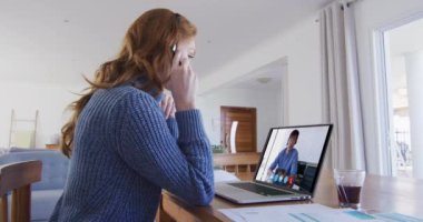 Beyaz bir kadın, erkek arkadaşıyla konuşurken bilgisayar ve kulaklık kullanıyor. Karantina süresince evde tek başına kalmak..
