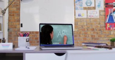 Video görüşmesi sırasında dizüstü bilgisayarda gösterilen karışık ırk bayan öğretmeni. Çevrimiçi eğitim karantina süresince evde tek başına kalıyor..