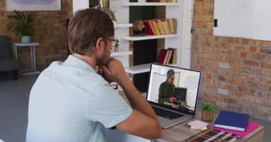Beyaz erkek öğrenci erkek öğretmenle video görüşmesinde dizüstü bilgisayar kullanıyor. Çevrimiçi eğitim karantina süresince evde tek başına kalıyor..