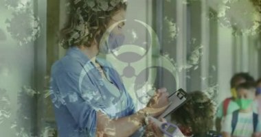Biyolojik tehlike işareti. 19 hücre, kadın öğretmen ve maskeli okul çocukları. Coronavirus covid 19 salgını sırasında sağlık ve korunma, dijital olarak üretilen video.