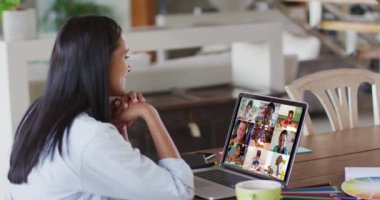 Beyaz kadın öğretmen okul çocuklarıyla video görüşmesinde dizüstü bilgisayar kullanıyor. Çevrimiçi eğitim karantina süresince evde tek başına kalıyor..