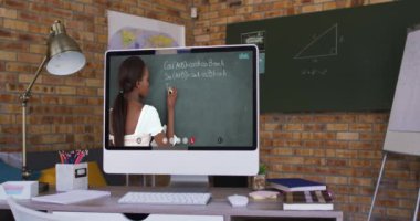 Video görüşmesi sırasında bilgisayar ekranında karışık ırk öğretmeni. Çevrimiçi eğitim karantina süresince evde tek başına kalıyor..