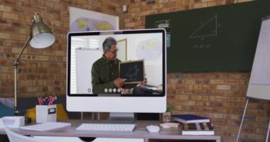 Video görüşmesi sırasında melez bir erkek öğretmen bilgisayar ekranında görüntülendi. Çevrimiçi eğitim karantina süresince evde tek başına kalıyor..