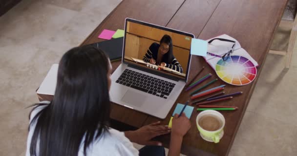 Kavkazská učitelka používající notebook na videohovoru se studentkou, dělá si poznámky. Online vzdělávání zůstat doma v izolaci během karantény uzamčení.