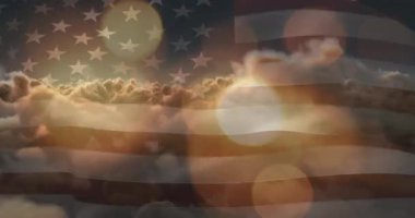 Amerikan bayrağının üzerinde bulutlarla parlayan güneş ve parlayan noktaların animasyonu. Vatanseverlik kavramı dijital olarak oluşturulmuş video.