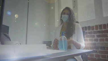 Ofiste el dezenfektanı kullanan yüz maskesi takan Hintli bir kadına karşı ışığın yer aldığı dijital video. Coronavirus covid-19 salgını sırasında işyerinde hijyen ve sosyal mesafeler