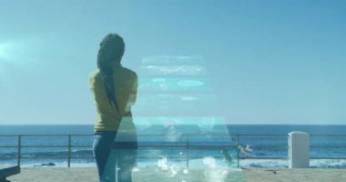 Deniz kenarında yürüyen bir kadının üzerinde süzülen ekranların animasyonu. Dijital arayüz küresel spor ve performans konsepti dijital olarak oluşturulmuş video.