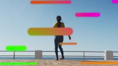 Deniz kenarındaki gezinti güvertesinde dans eden kadın üzerinde yüzen renkli şekillerin animasyonu. dijital arayüz küresel spor ve performans konsepti dijital olarak oluşturulmuş video.