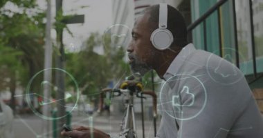 Şehir caddesinde oturan kulaklıklı ve akıllı telefonlu adam üzerinde dijital simgelerin canlandırılması. küresel bağlantı ve iletişim konsepti dijital olarak oluşturulmuş video.