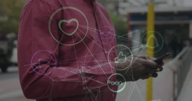 Akıllı telefon kullanarak Afro-Amerikan maskeli adam üzerinden dijital simge ağının animasyonu. küresel covid 19 salgın, ağ, iletişim ve bağlantı konsepti dijital olarak oluşturulmuş video.