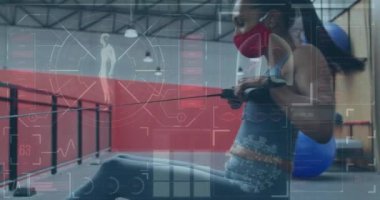 Yüz maskesi takan beyaz bir kadın için istatistik ve grafiklerin animasyonu çalışıyor. Dijital olarak üretilen küresel covid 19salgın konsepti.