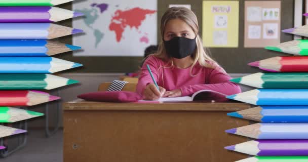 Анимация Цветных Карандашей Над Девушкой Маске Лица Сидящей Классе Пишущей — стоковое видео