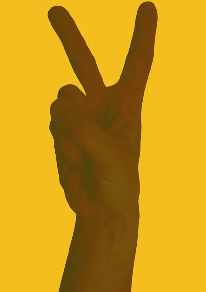 Close up of hand showing victory sign on yellow background. freedom and equality concept digitally generated image.