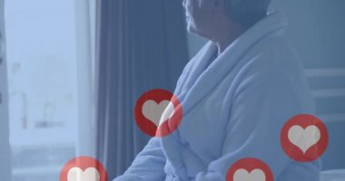 Yatakta arka planda oturan yaşlı kadının kalp aşk ikonlarının canlandırması. dijital arayüz, bağlantı ve iletişim konsepti dijital olarak oluşturulmuş video.