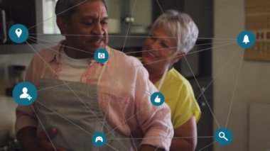Mutfakta eğlenen yaşlı çiftin bağlantı ikonlarının animasyonu. dijital arayüz, sosyal medya, küresel bağlantı ve dijital olarak oluşturulmuş iletişim konsepti.