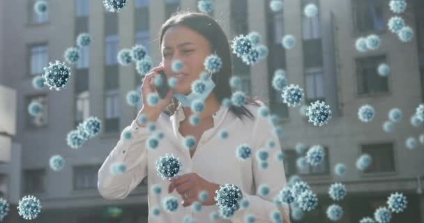 スマートフォンで話す顔のマスクを下げている女性に対して浮くCovid 19細胞 コロナウイルスは19種のパンデミックの概念を — ストック動画