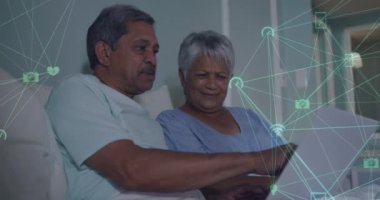 Evde dizüstü bilgisayar kullanarak yaşlı çiftin üzerinde dönen bağlantı ağlarının animasyonu. küresel ağ, bağlantı ve iletişim konsepti dijital olarak oluşturulmuş video.