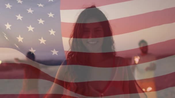Κινούμενο σχέδιο της αμερικανικής σημαίας κυματίζει πάνω από την ομάδα των γυναικών που κατέχουν sparkler στην παραλία — Αρχείο Βίντεο