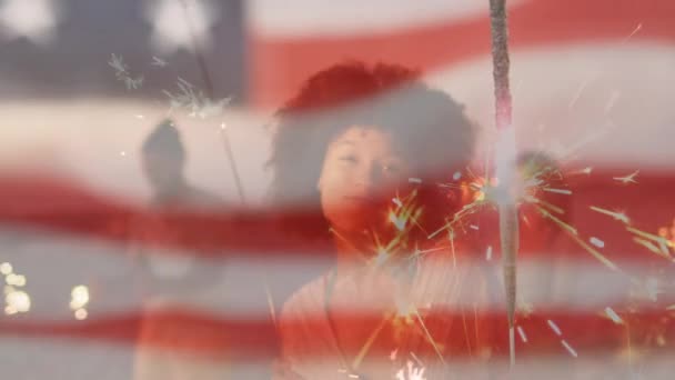 Animazione di bandiera americana sventola sulla donna che tiene scintille sulla spiaggia — Video Stock