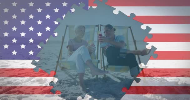 Animacja Amerykańskiej Flagi Puzzli Odsłaniających Parę Seniorów Drinkami Leżakach Plaży — Wideo stockowe