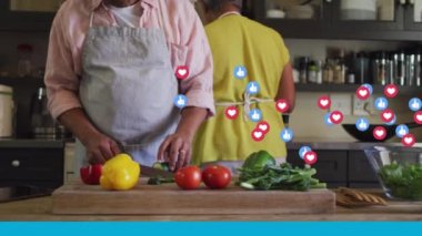 Evde, mutfakta birlikte yemek pişiren yaşlı çifte karşı yüzen birden fazla dijital simge. Sosyal medya ağı ve teknoloji kavramı