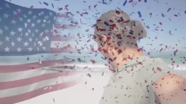 Amerikan bayrağının dalgalanması ve konfetilerin kumsalda gülümseyen yaşlı adamın üzerine düşmesi. ABD, vatanseverlik ve kutlama konsepti dijital olarak oluşturulmuş video.