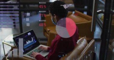 Ofiste dizüstü bilgisayar kullanarak yüz maskesi takan kadın hakkında istatistiksel veri işleme