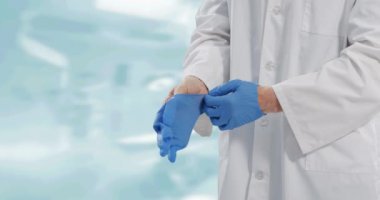 Beyaz arka plana cerrahi eldiven takan erkek doktorun orta bölümü. Tıbbi yeniden ölçüm ve covid 19 salgın konsepti