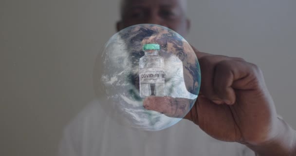 Covi 19ワクチンを保有するアフリカ系アメリカ人男性の肖像画に対して地球を回転させます コロナウイルスCovid 19パンデミックの概念 — ストック動画