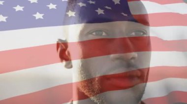 Gülümseyen Afro-Amerikan bir adamın üzerinde Amerikan bayrağının dalgalanması. ABD vatanseverliği ve demokrasi kavramı dijital olarak oluşturulmuş video.