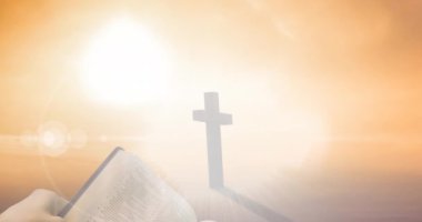 Hristiyan haçı animasyonu ve turuncu arka planda parlak lekeli İncil okuyan kişi. Paskalya kutlaması, din ve gelenek kavramları dijital olarak oluşturulmuş video.