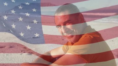 Sahilde gülümseyen son sınıf öğrencisinin üzerinde Amerikan bayrağının dalgalanması. ABD vatanseverliği ve demokrasi kavramı dijital olarak oluşturulmuş video.