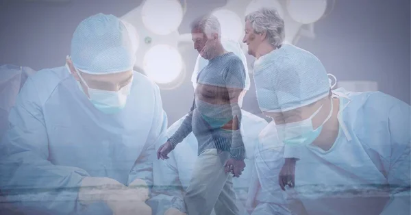 Zespół Chirurgów Wykonujący Operację Szpitalu Przeciwko Parze Seniorów Spacerujących Plaży — Zdjęcie stockowe