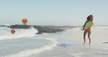 Animation of heart digital icons over couple running with surfboards on beach. digital interface, social media and global technology concept digitally generated video.