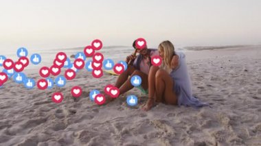 Multiple heart and like icons floating against caucasian couple drinking beer on the beach. social media networking and vacation concept