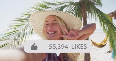 Animation of speech bubble with thumbs up icon and numbers over smiling woman on beach. digital interface, social media and global network concept digitally generated video.