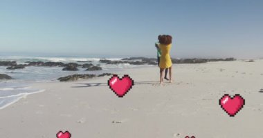 Animation of heart digital icons over couple dancing on beach. digital interface, social media and global technology concept digitally generated video.