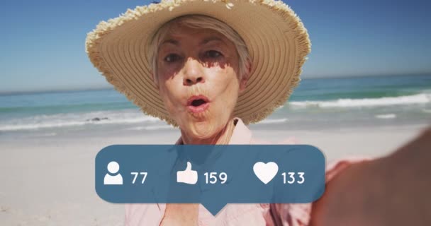 人们的动画 大拇指和心脏图标与数字超过老年妇女在沙滩上的草帽 数码界面 社交媒体和全球技术概念 — 图库视频影像
