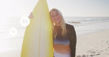 Animation of social media email icons over smiling woman holding surfboard on beach. digital interface, social media and global network concept digitally generated video.