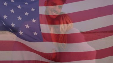 Kumsalda birbirini kucaklayan beyaz çifte karşı Amerikan bayrağı sallıyor. Amerika 'nın bağımsızlığı vatansever tatil konsepti