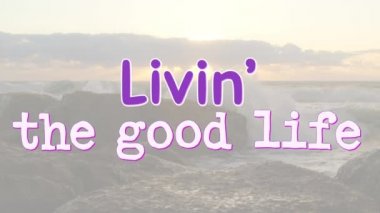 Sözcüklerin animasyonu, gün batımında deniz manzarasında mor ve beyaz bir şekilde yazılmış güzel bir hayatı yaşamaktır. pozitif duygular, doğa ve refah konsepti, dijital olarak oluşturulmuş video.