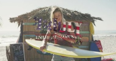 Amerikan bayrağı sahilde sörf tahtası olan beyaz bir kadına karşı bağımsızlık günü mesajı sallıyor. Amerika 'nın bağımsızlığı vatansever tatil konsepti