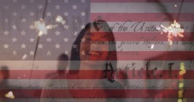 Sahilde havai fişeklerle eğlenen kadınlara karşı Amerikan bayrağı ve anayasa metni sallamak. Amerika 'nın bağımsızlığı vatansever tatil konsepti