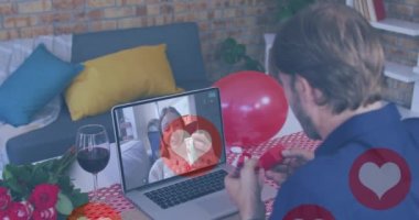 Kafkasyalı adamın üzerinde yüzen kalp simgeleri dizüstü bilgisayarında bir video görüşmesi yaparken yüzük gösteriyor. Sevgililer Günü 'nün uzak kutlaması online ve flört konsepti