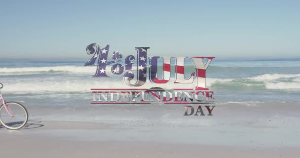 美国国旗飘扬独立日文字反对妇女骑自行车在海滩上 美国独立爱国假日的概念 — 图库视频影像