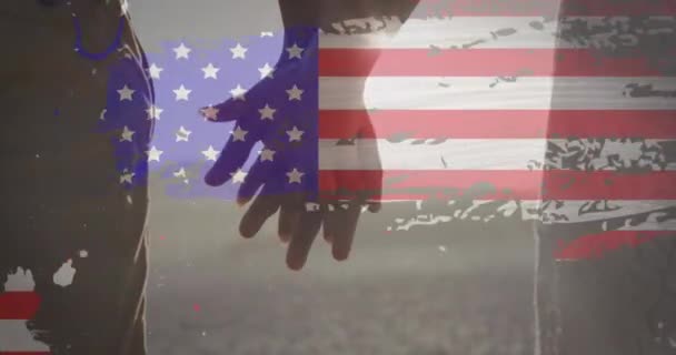 ビーチで手を握っているカップルの中央部に対するグリッチ効果を持つアメリカ国旗 アメリカ独立の愛国的休日の概念 — ストック動画