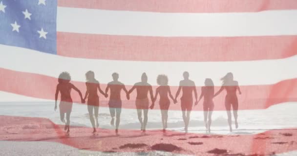 Американский Флаг Размахивающий Против Группы Друзей Держащихся Руки Бегущих Вместе — стоковое видео