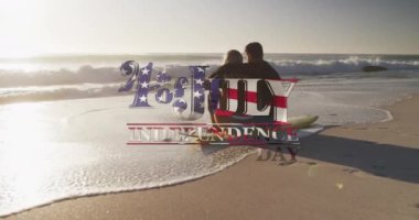 Amerikan bayrağı sahilde sörf tahtasında oturan çifte karşı bağımsızlık günü mesajı sallıyor. Amerika 'nın bağımsızlığı vatansever tatil konsepti